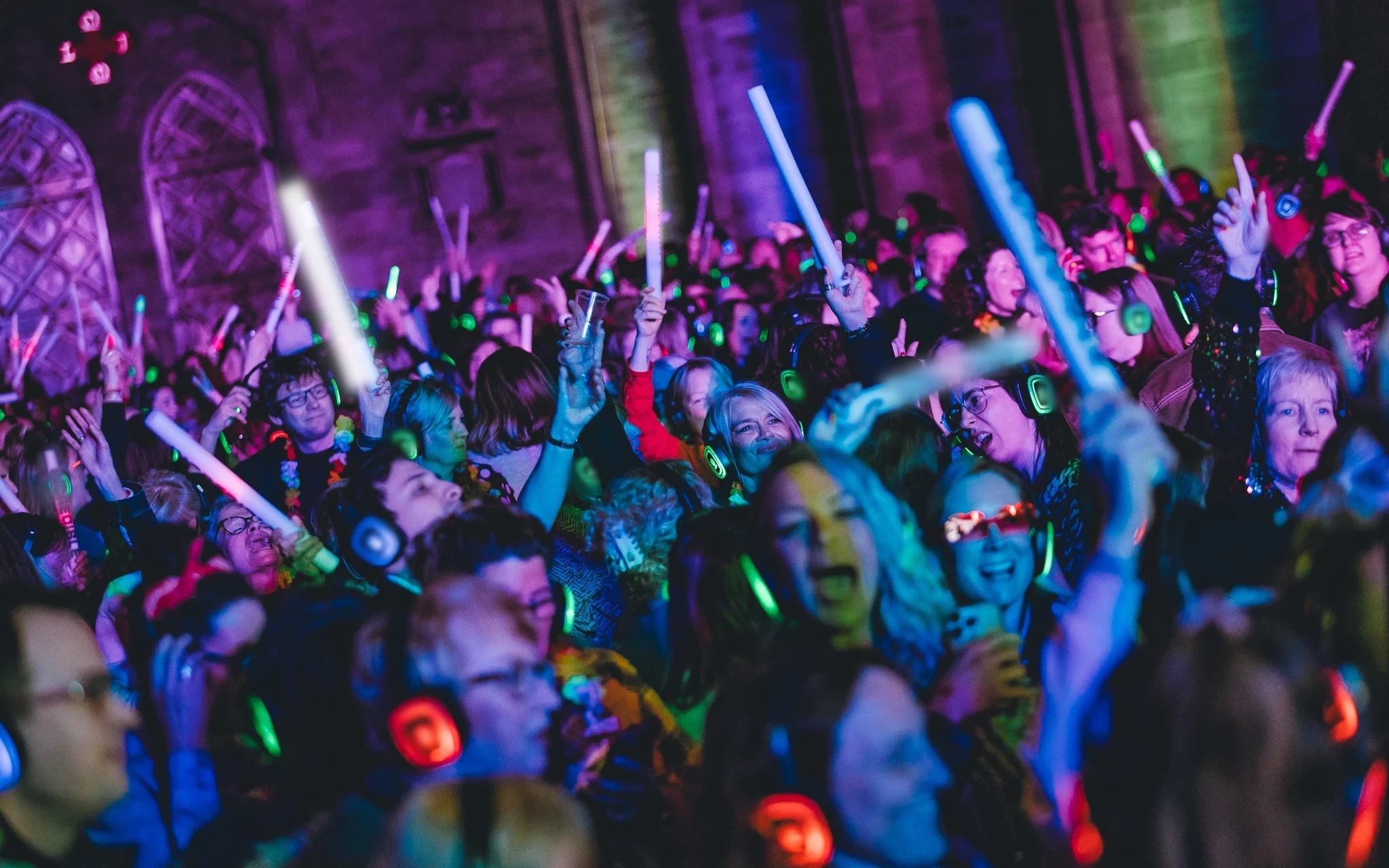 Multidão a dançar num evento SilentWave, com auscultadores iluminados e luzes coloridas